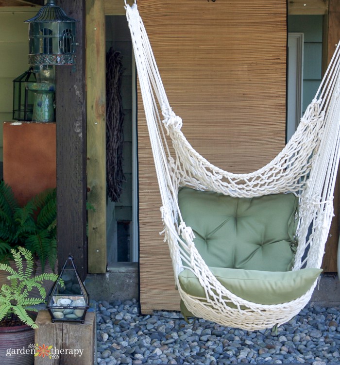 White Macrame Hammock Chair με ένα πράσινο μαξιλάρι σε μια αυλή