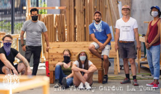 Η ομάδα Victory Garden LA που κρέμονται γύρω, μερικοί στέκονται και μερικοί κάθονται σε κρεβάτια κήπου.
